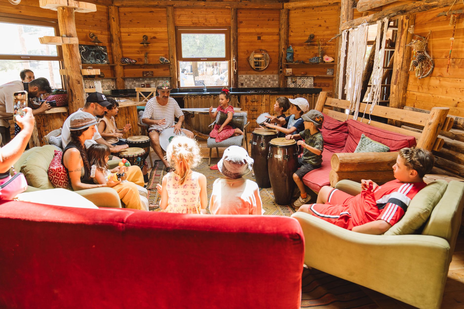 A lively drum session with children learning music in a cozy wooden room.