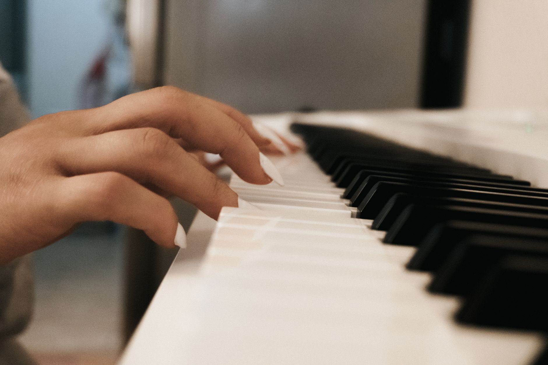 A close-up shot of hands playing a digital piano indoors with focus on the keys.