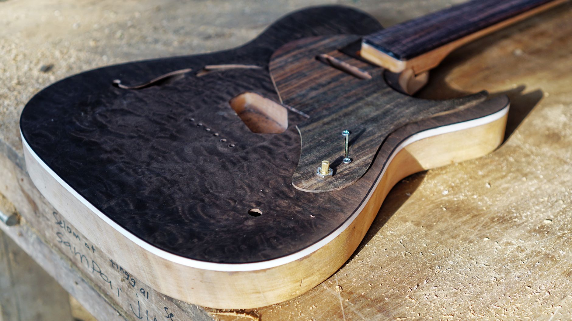 Close-up of a handcrafted electric guitar body on a wooden workbench, highlighting woodwork detail.