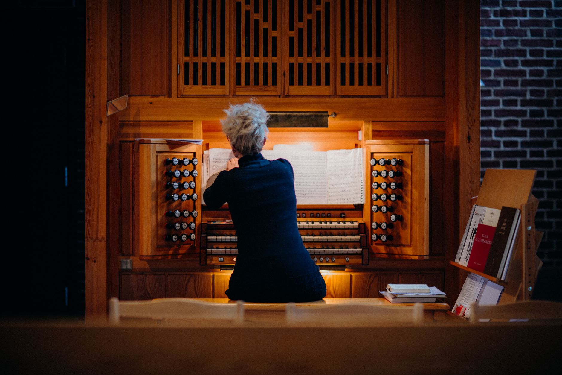 A woman plays a pipe organ inside a church, showcasing intricate musical details.