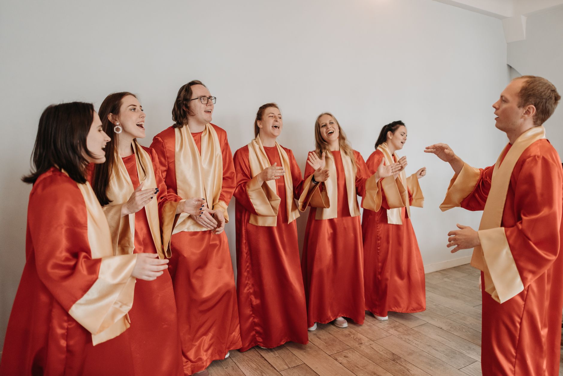 A group of adults in red gowns singing passionately indoors, embodying spiritual harmony.