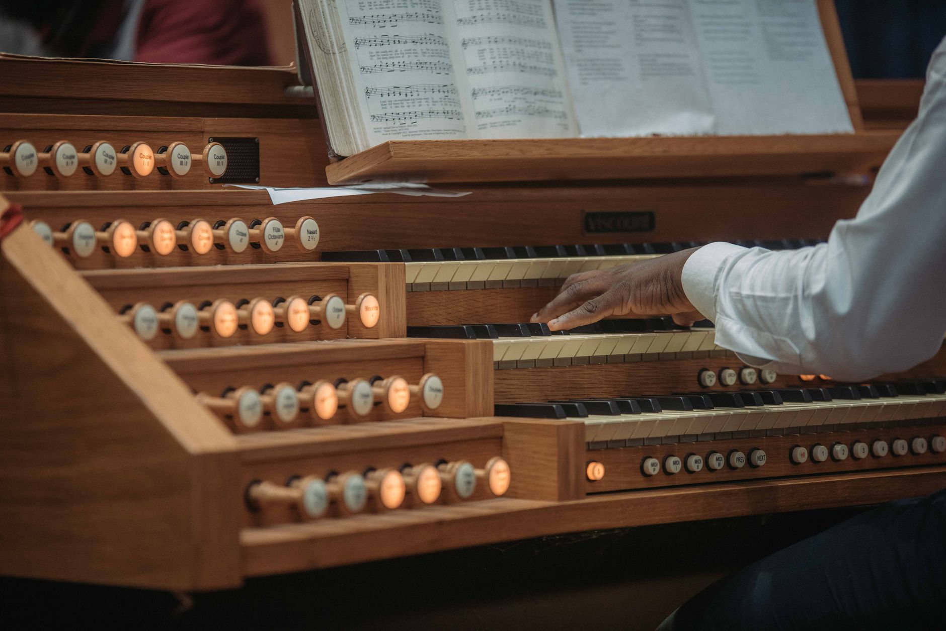An organist skillfully playing classical music on a wooden organ indoors.
