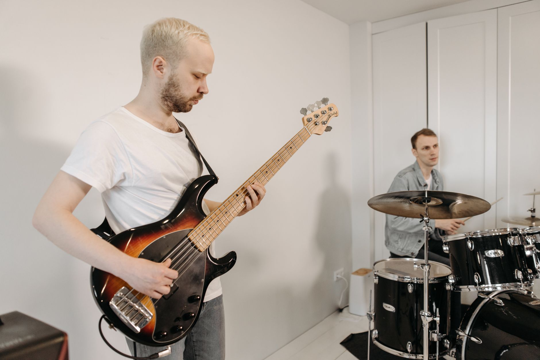 Two musicians playing guitar and drums during a home jam session.