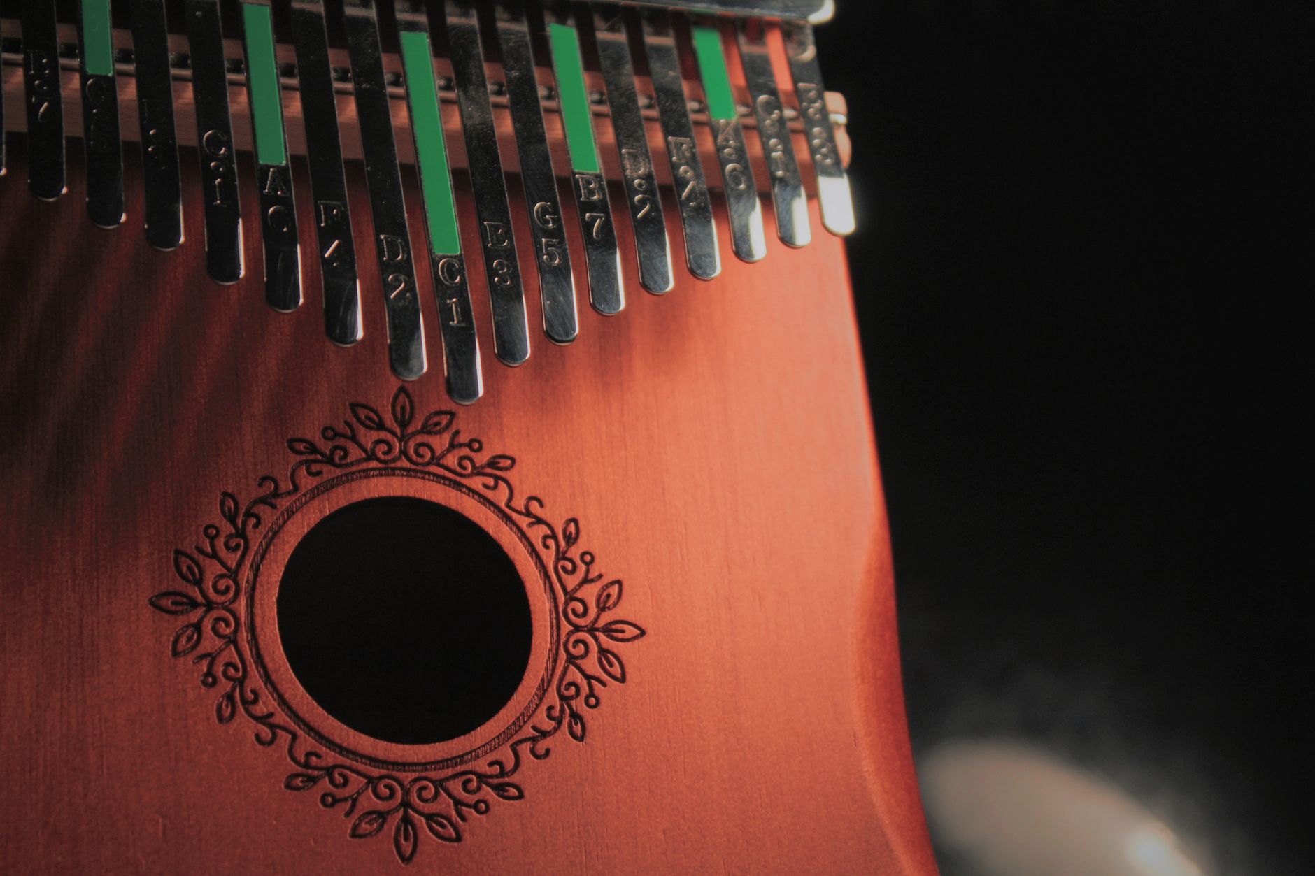 Close-up view of a wooden kalimba with metal tines and decorative cut-out, showing intricate details.