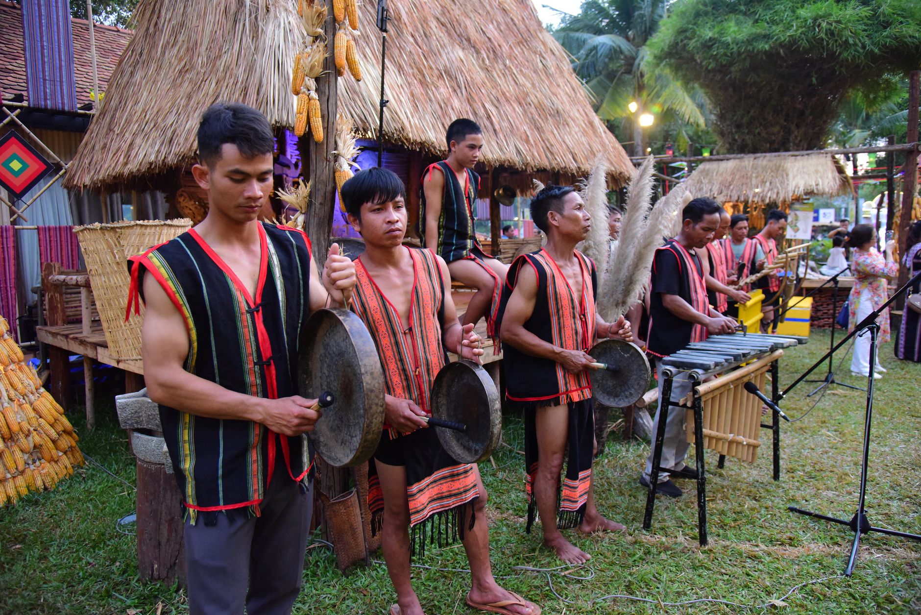 Group of musicians in traditional attire performing with instruments outdoors during a cultural festival.