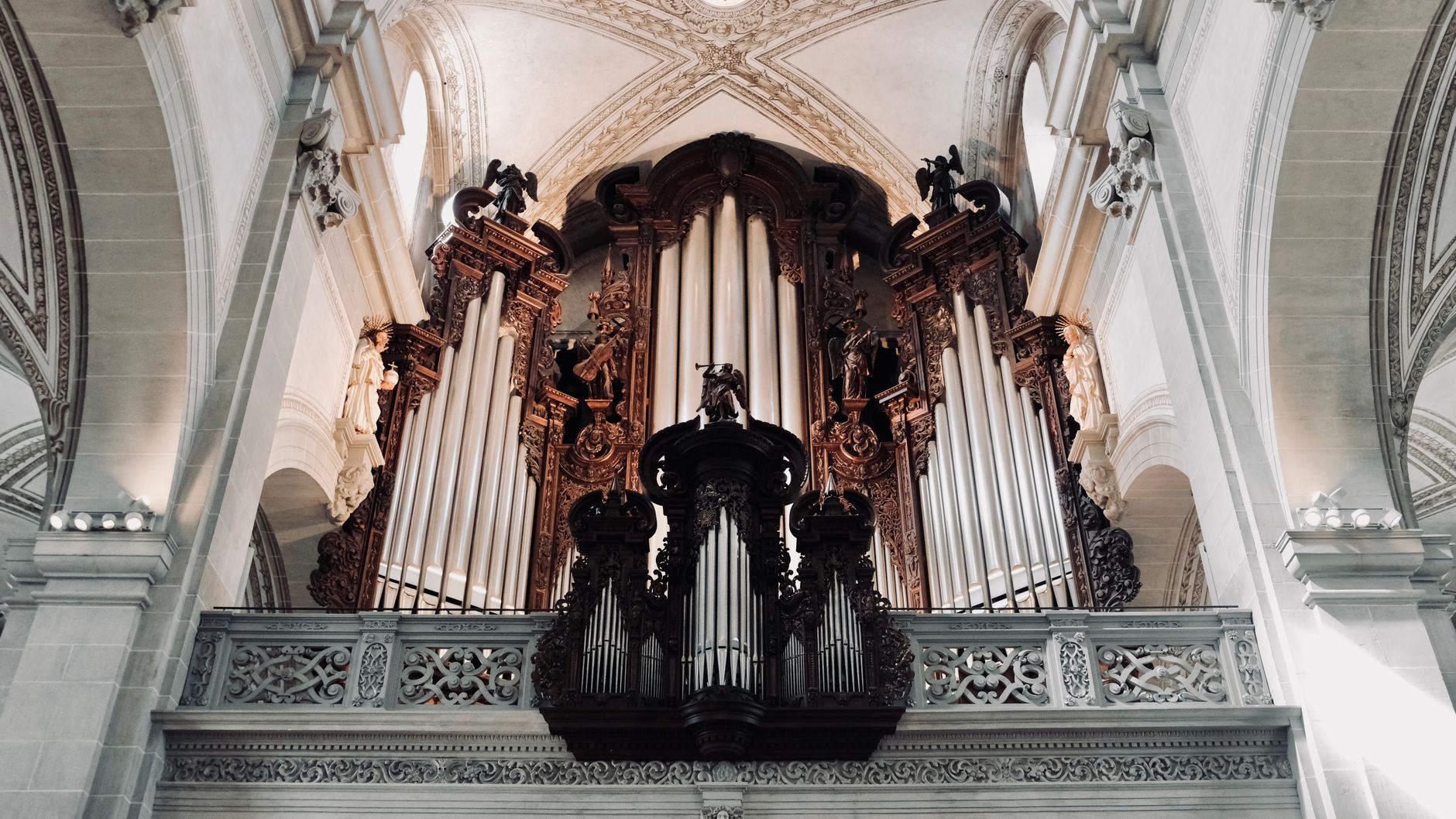 Intricate baroque pipe organ in a majestic cathedral interior with ornate details.