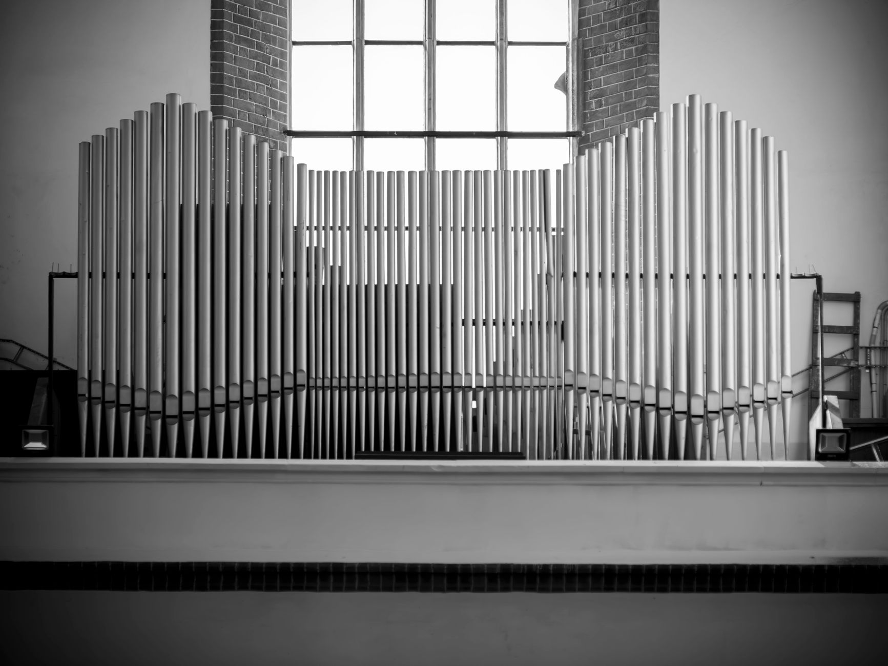 Monochrome image of a pipe organ inside a Polish church, empty interior view.