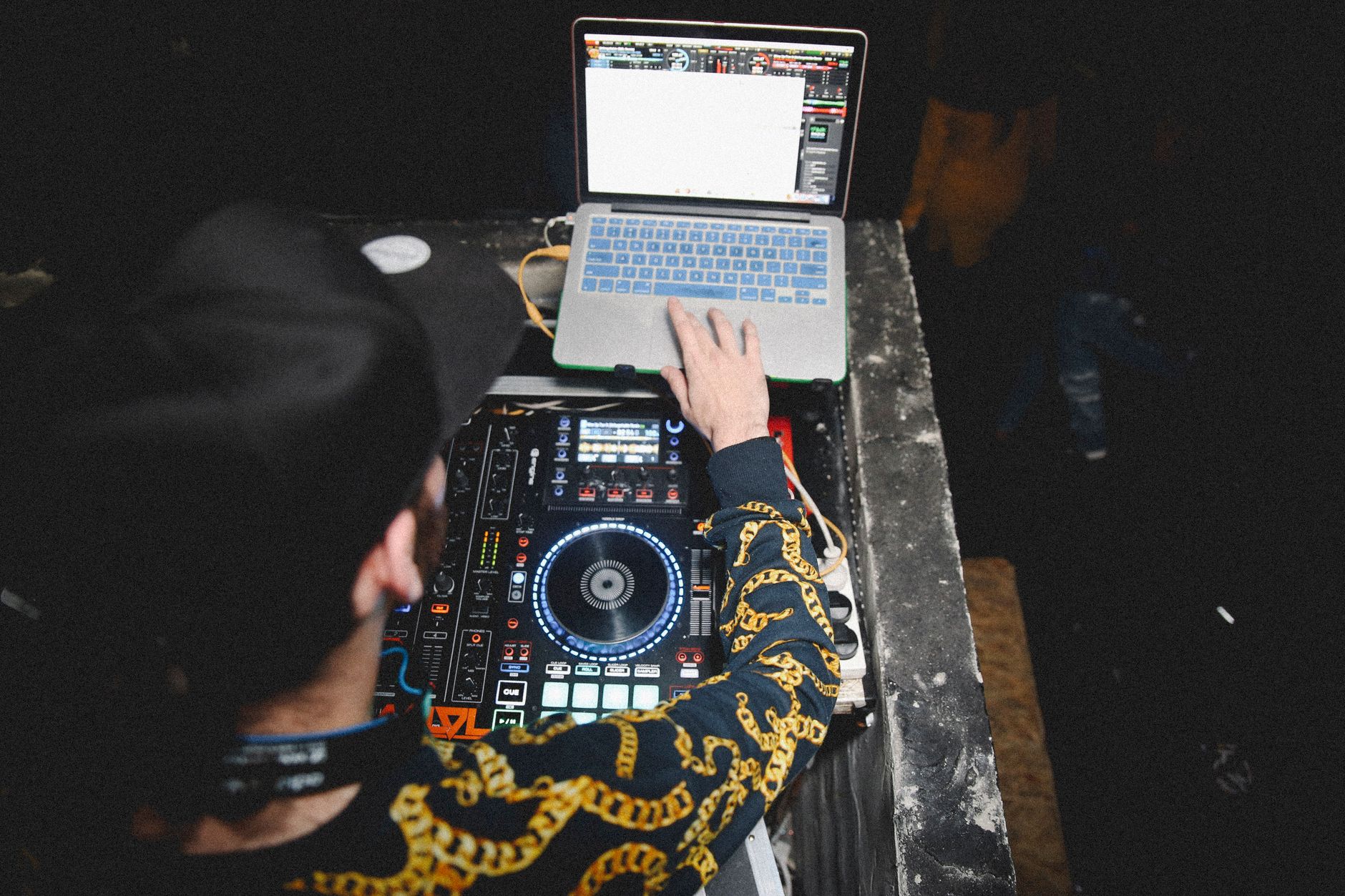 A DJ uses a laptop and mixing console during a vibrant live music event.