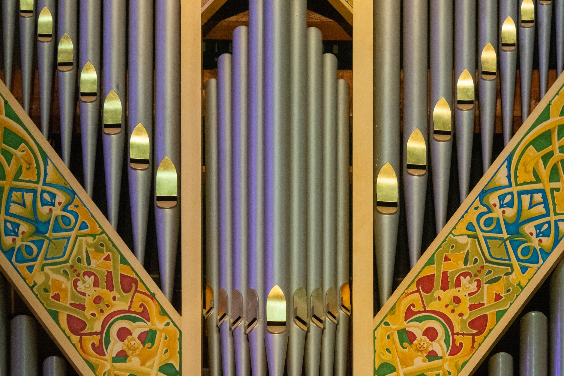 Captivating image of a classic church pipe organ featuring intricate colorful decorations.