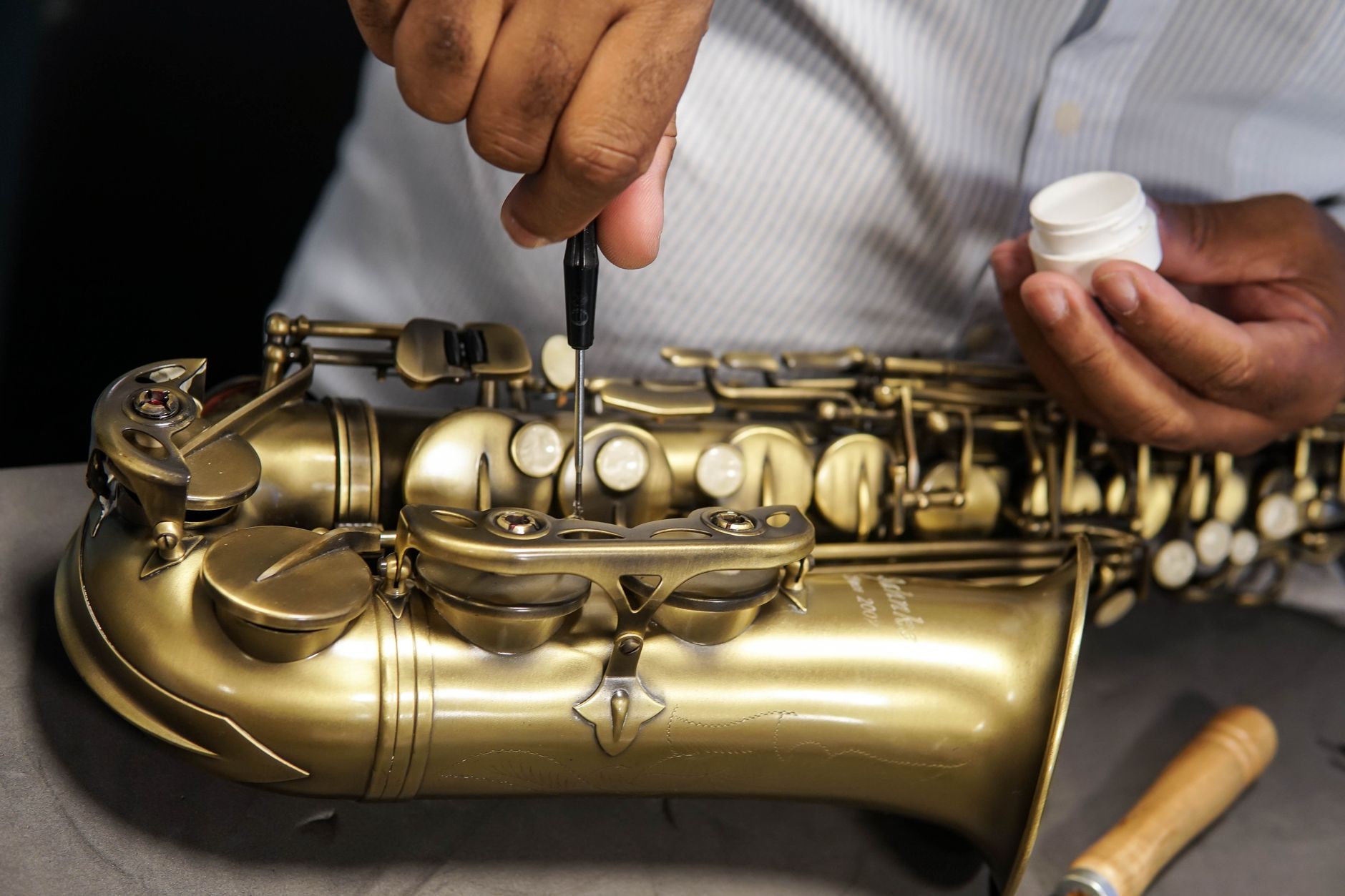 A skilled technician repairing a saxophone, showcasing craftsmanship and expertise in musical instrument maintenance.