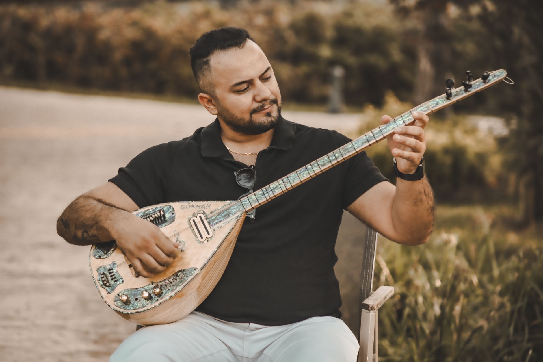 A man plays a Turkish Baglama in an outdoor setting, creating a serene musical atmosphere.