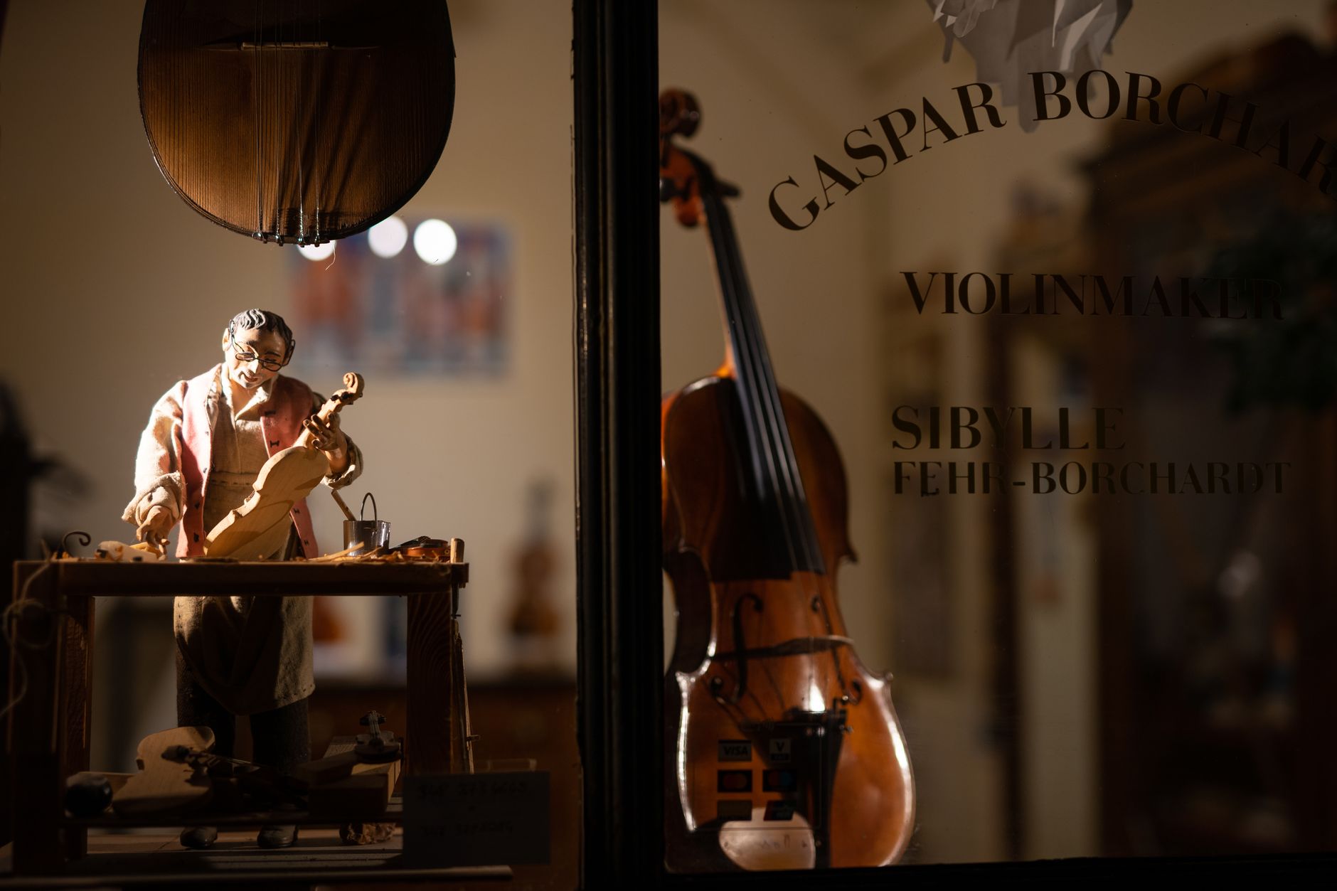 Close-up of a violinmaker's workshop with a figurine and instruments in Cremona, Italy.