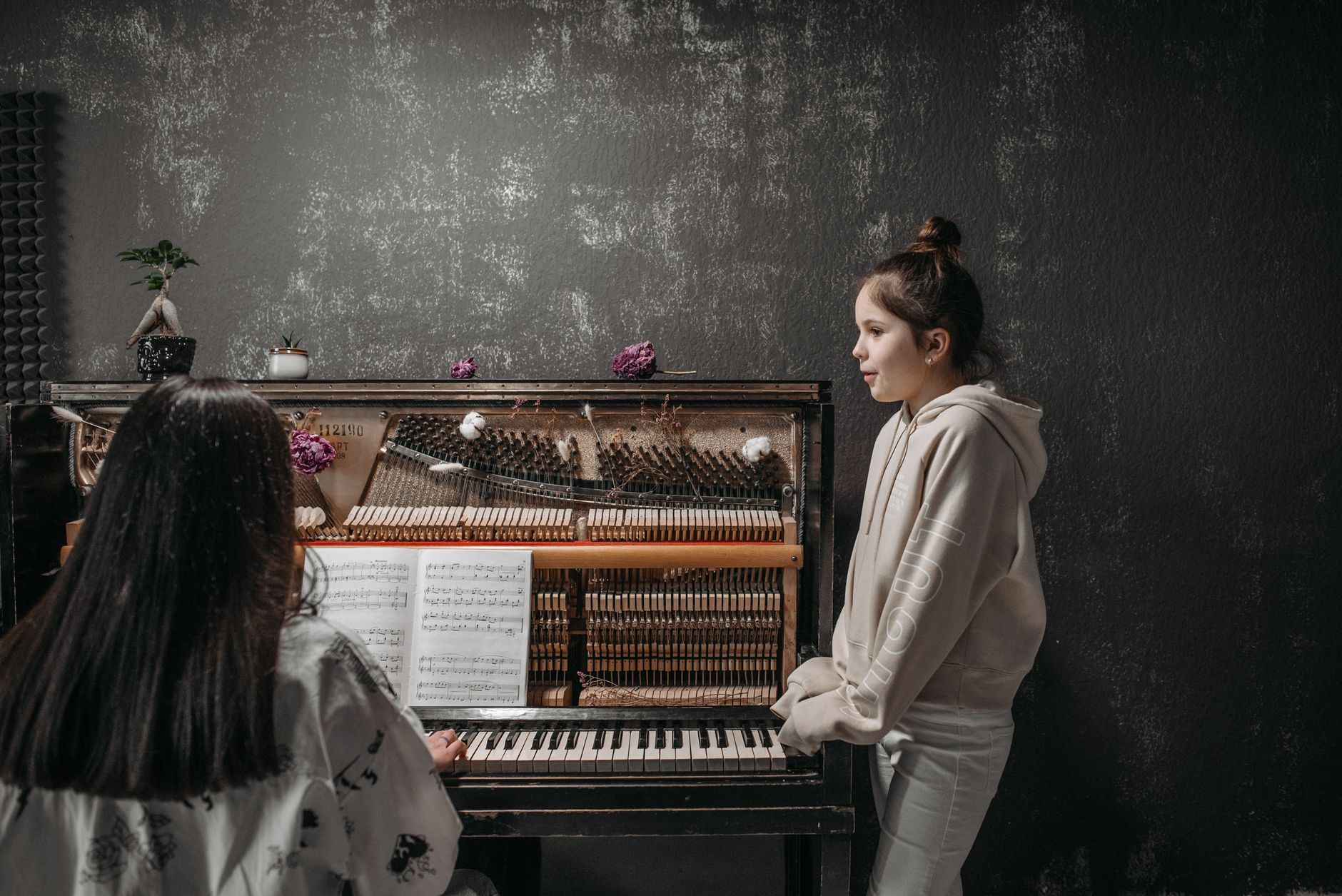A young girl receiving piano lessons with a teacher in a music studio setting.
