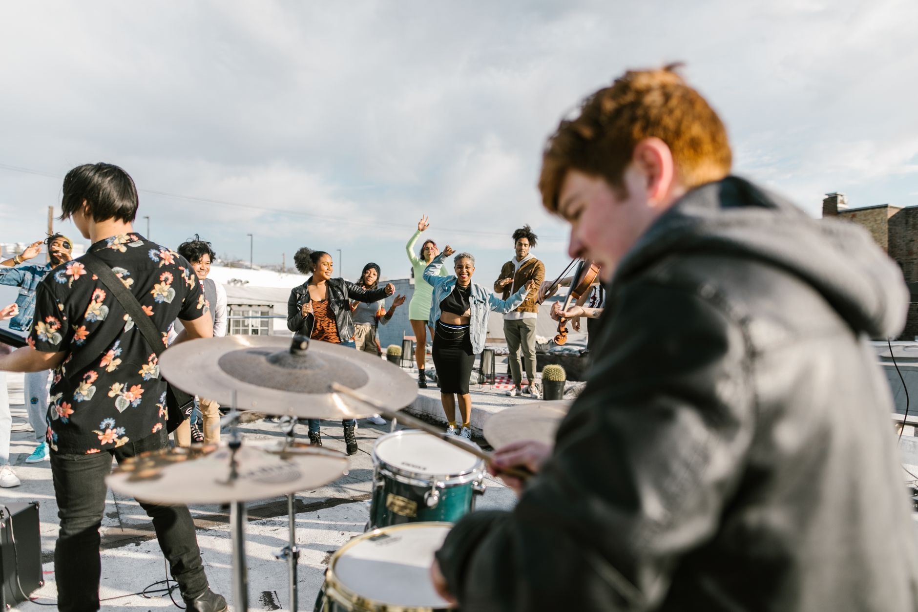 A diverse group of musicians playing instruments on a sunny rooftop, evoking a lively and festive atmosphere.