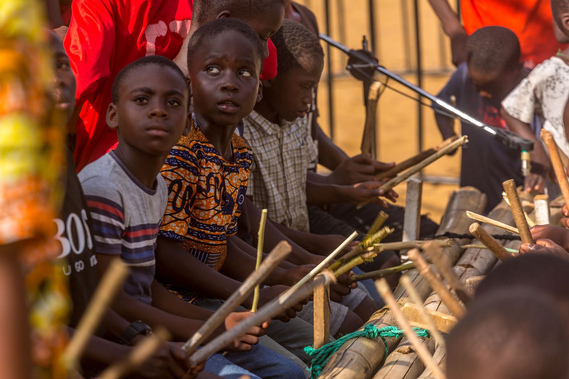 A group of children performing traditional music with wooden instruments outdoors.