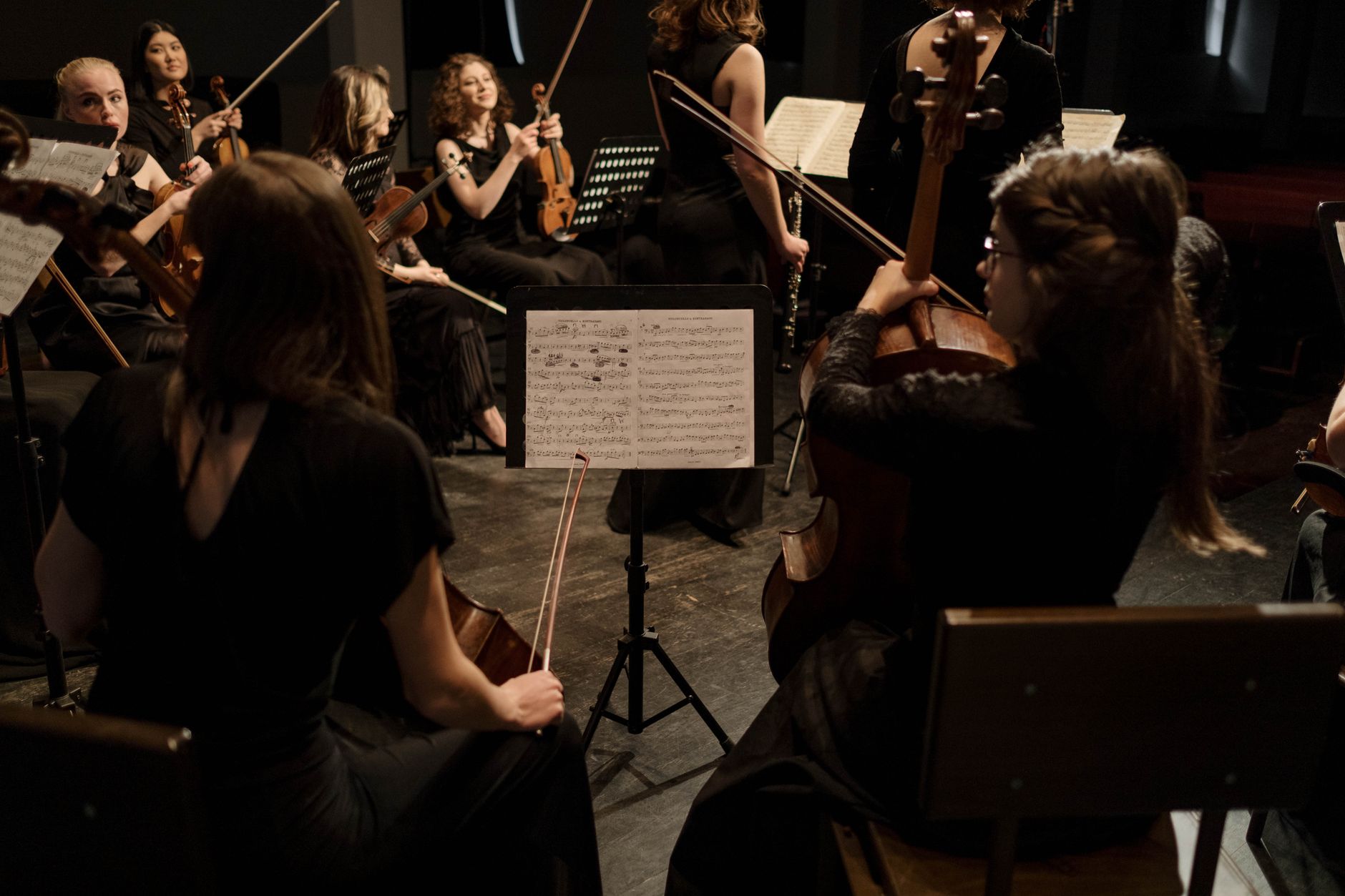 Group of musicians playing classical music with violins and cellos on stage in a concert.