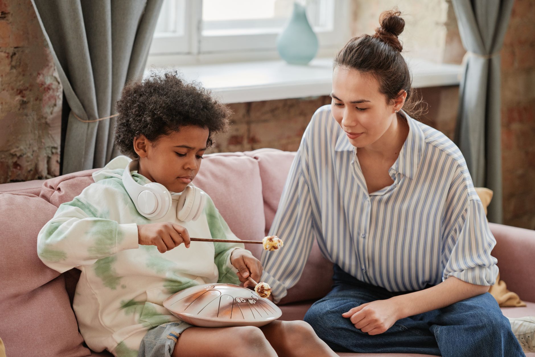 A mother and her child bonding indoors while playing a musical instrument together.