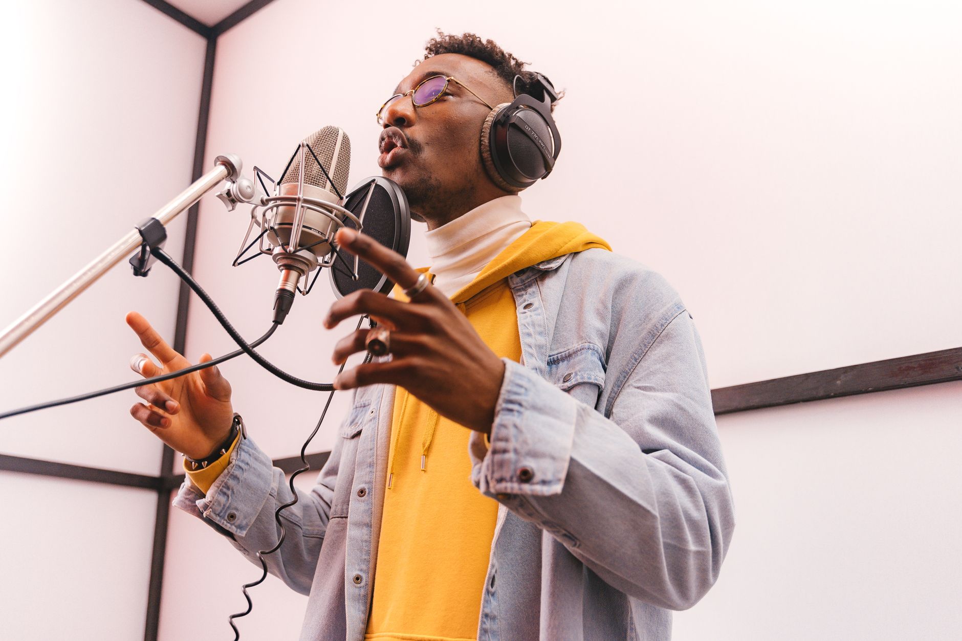 A focused young artist recording vocals in a professional music studio.