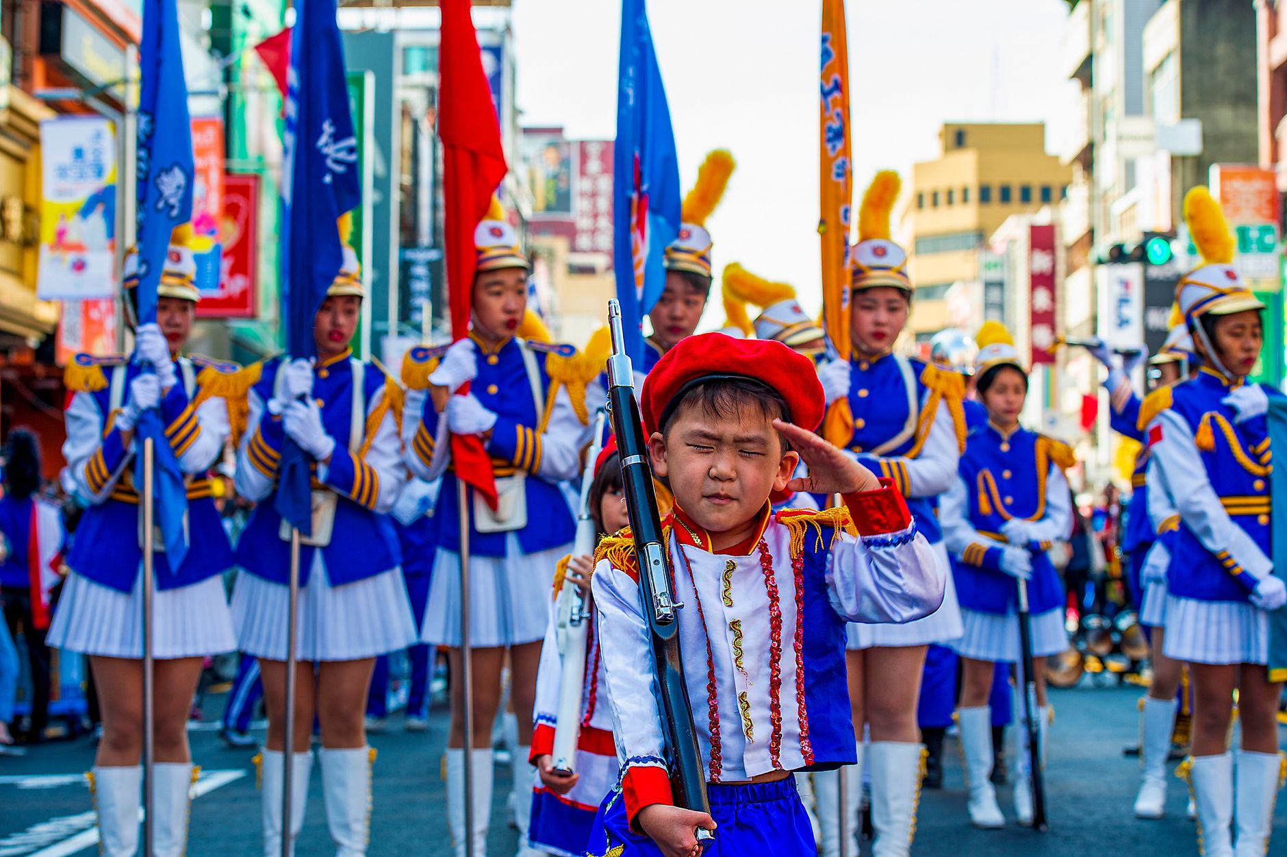Vibrant Taiwanese parade featuring children in elaborate marching band costumes and flags.