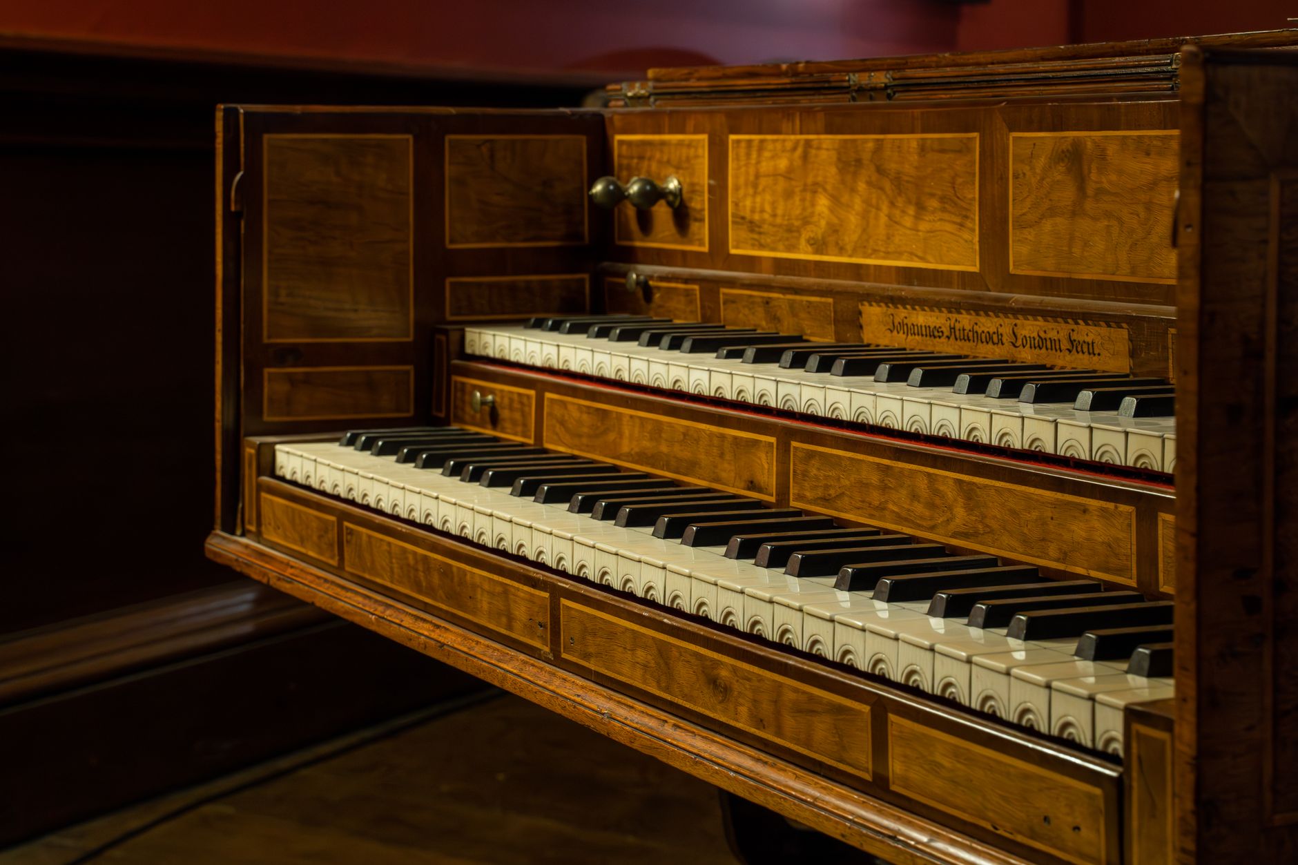 Close-up of an antique wooden keyboard instrument with intricate designs.