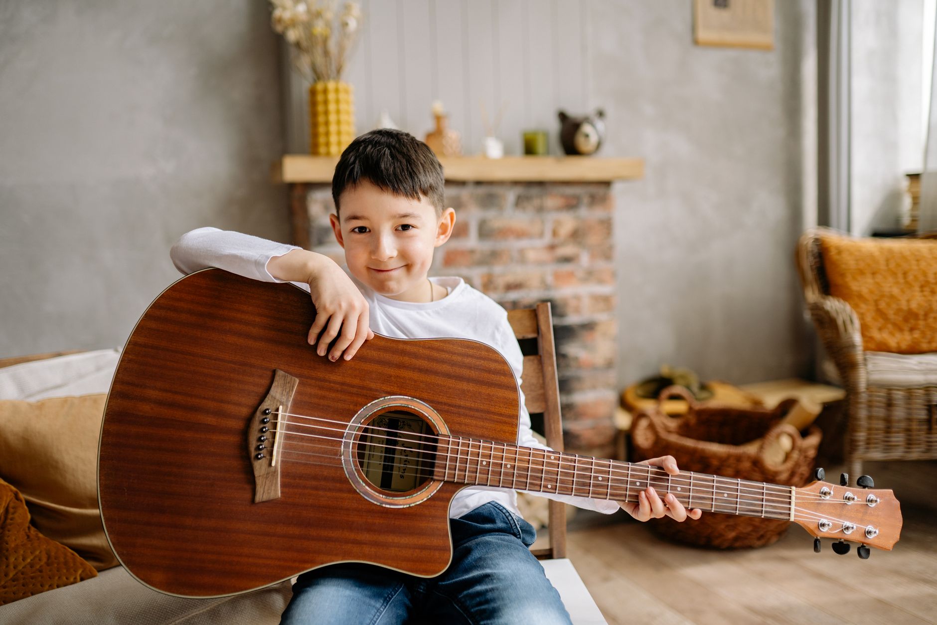 Child learning guitar indoors with an acoustic guitar. Cozy home setting.