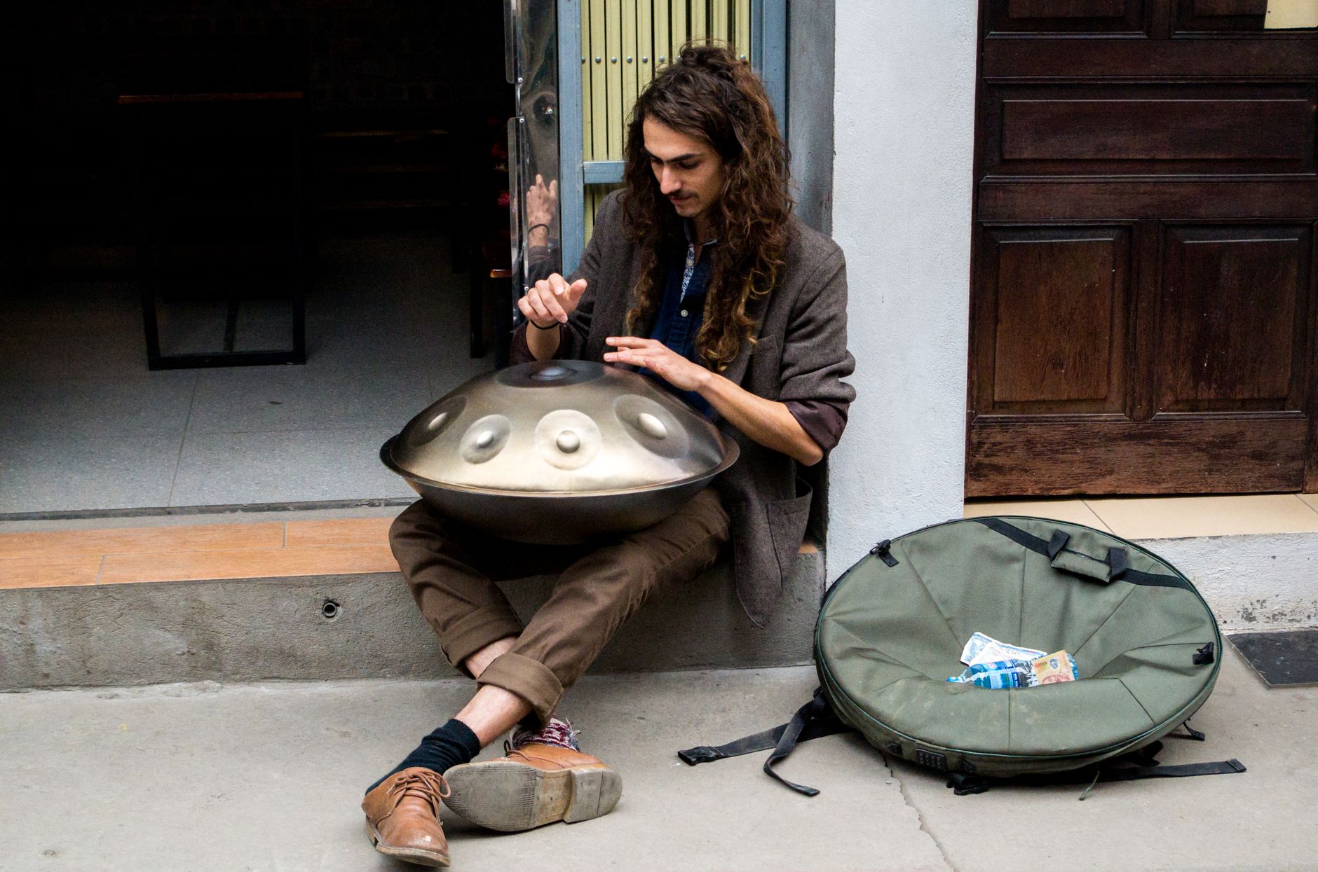 A man playing a hang drum on the sidewalk in Hanoi, Vietnam, creating soothing music.