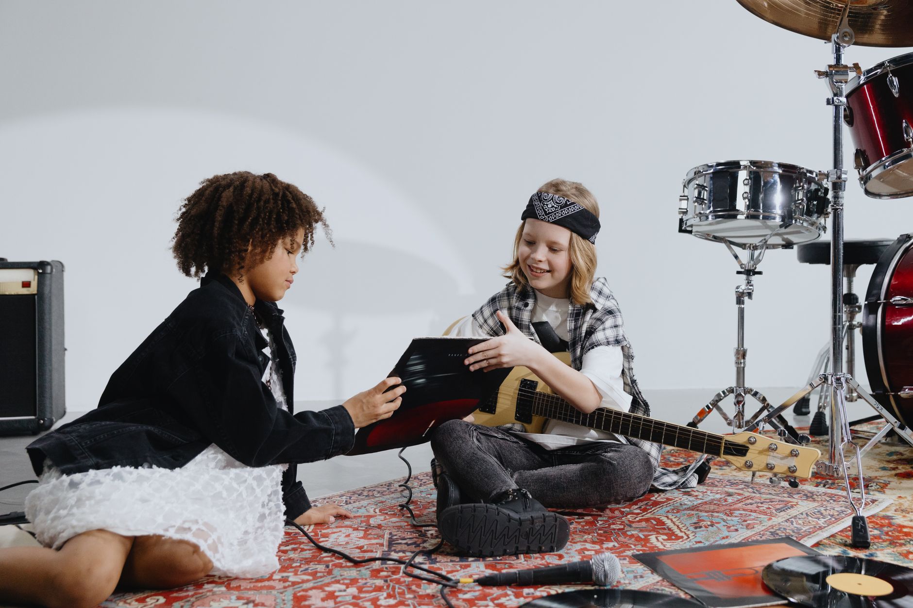 Two children in a music studio exploring instruments, emphasizing creativity and fun.