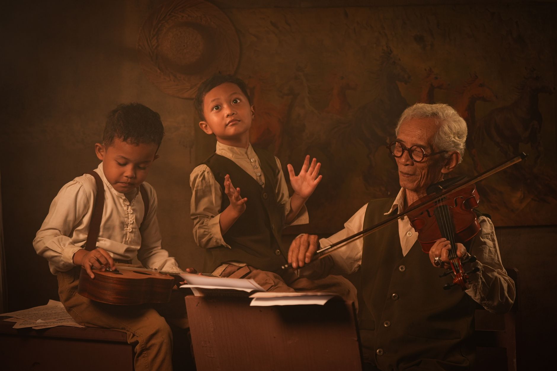 A senior adult and two children engaged in a music lesson with violin and ukulele indoors.