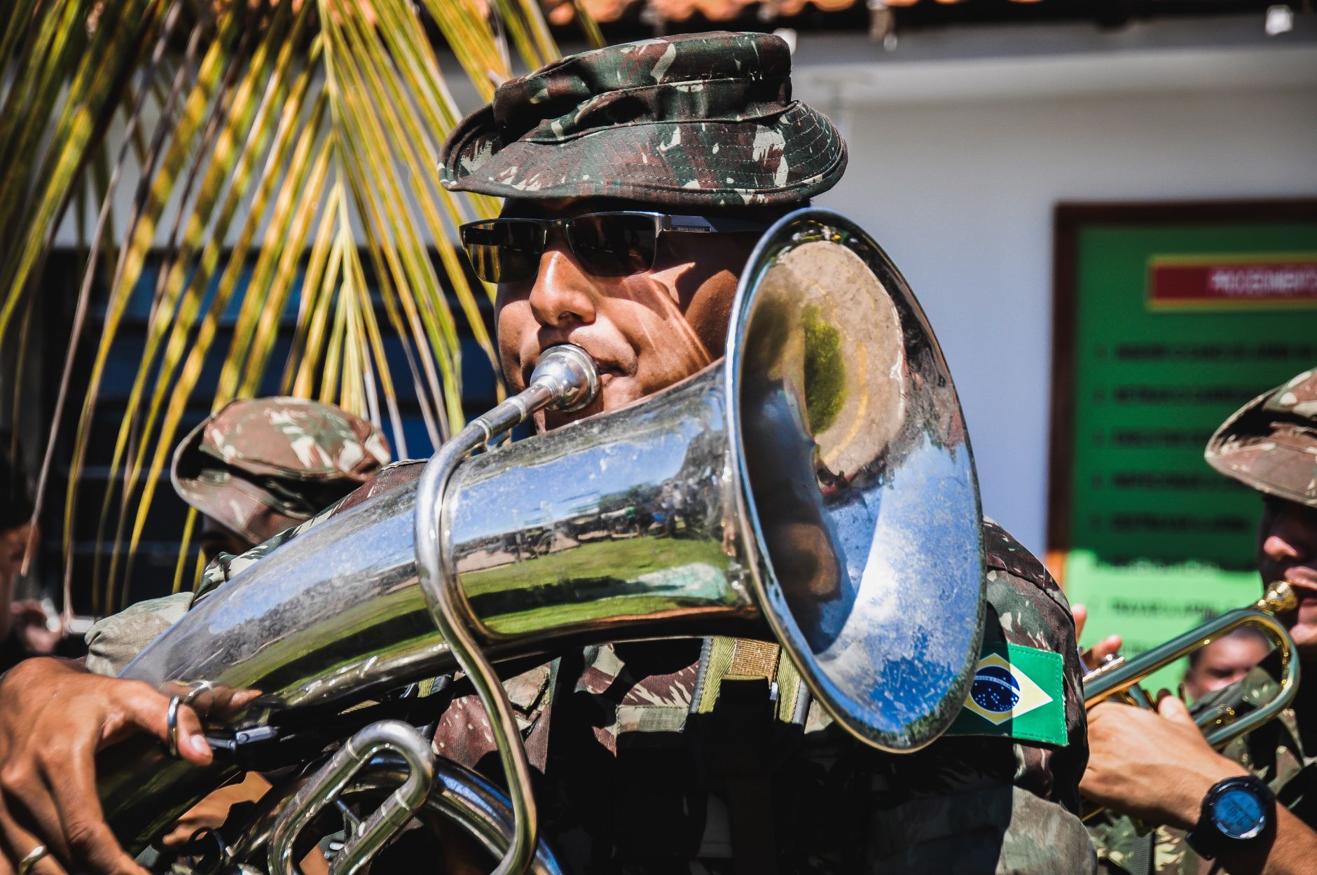 A military band musician in uniform plays the tuba outdoors during a celebration.